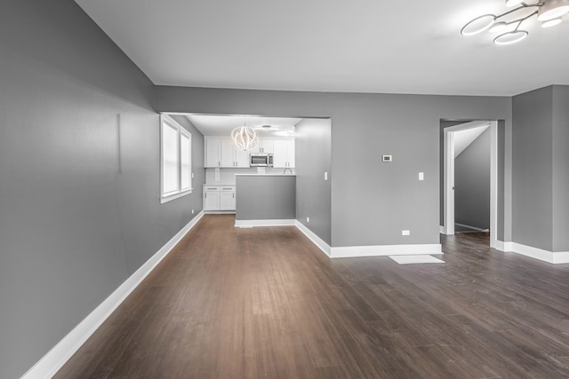 unfurnished living room featuring a chandelier and dark hardwood / wood-style flooring