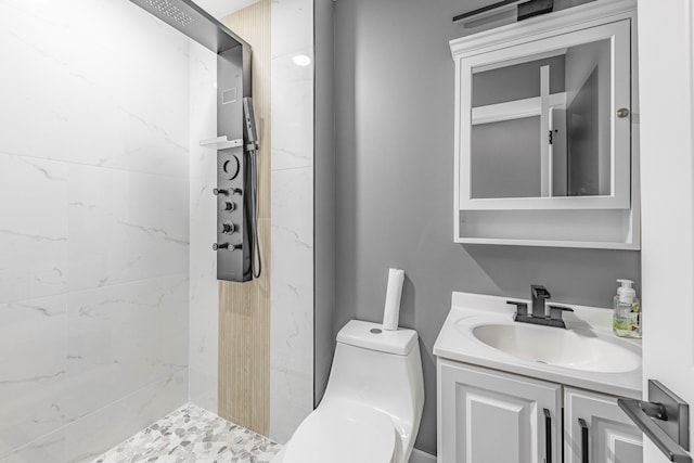 bathroom with vanity, toilet, and a tile shower