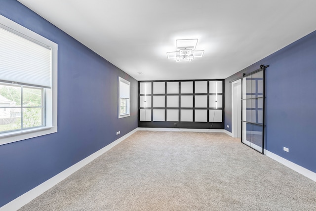 carpeted spare room featuring a barn door