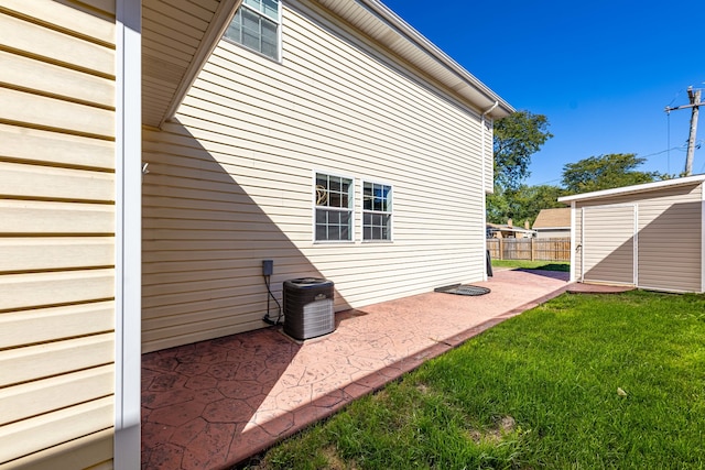 exterior space with a shed, a patio area, a lawn, and cooling unit