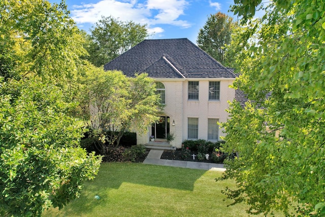 view of front facade featuring brick siding, roof with shingles, and a front yard