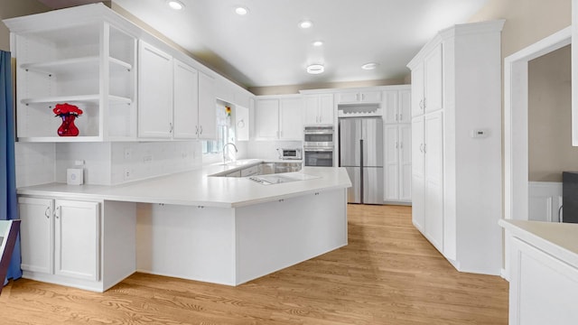 kitchen featuring light wood-type flooring, open shelves, stainless steel appliances, a peninsula, and light countertops