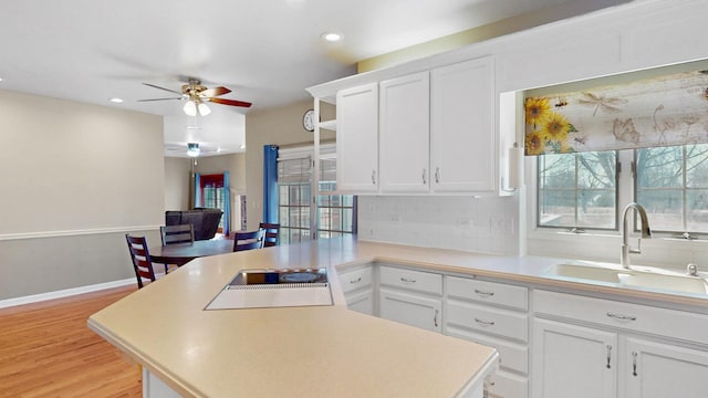 kitchen featuring a sink, white cabinetry, a peninsula, and light countertops