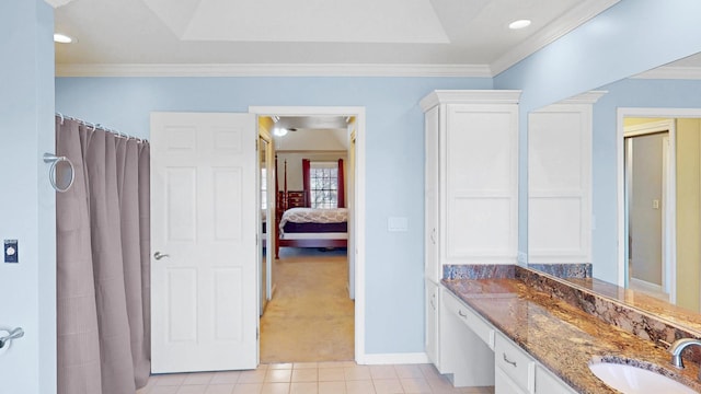 bathroom featuring tile patterned flooring, vanity, crown molding, and baseboards