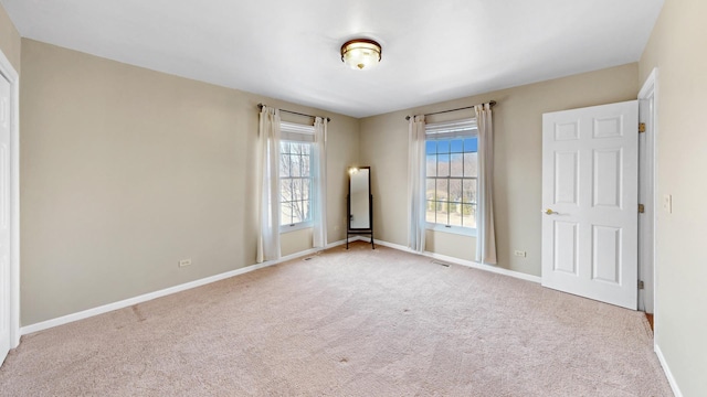 spare room with carpet flooring, visible vents, and baseboards