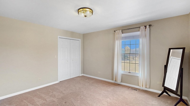 unfurnished bedroom featuring carpet flooring, baseboards, visible vents, and a closet