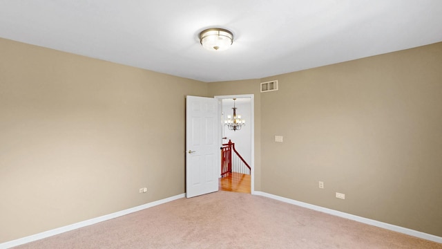 spare room with visible vents, light carpet, baseboards, and a chandelier