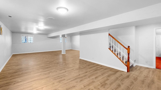 below grade area featuring visible vents, stairway, wood finished floors, and baseboards