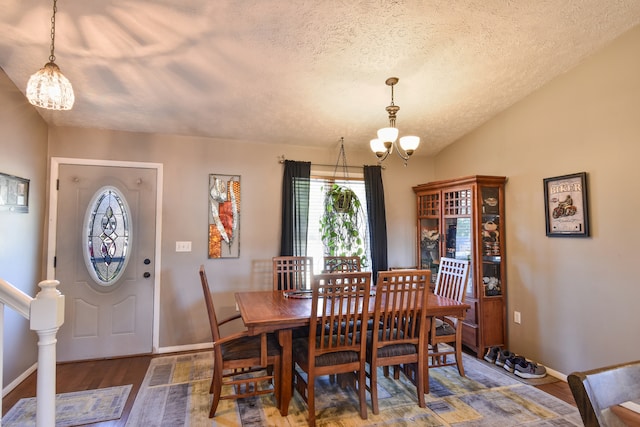 dining room with lofted ceiling, a textured ceiling, hardwood / wood-style flooring, and a chandelier