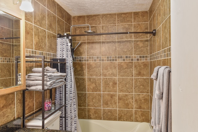 bathroom featuring a textured ceiling, shower / bathtub combination with curtain, and tile walls