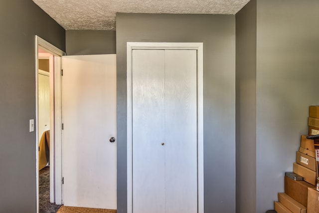 unfurnished bedroom with a textured ceiling, a closet, and carpet floors