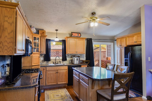 kitchen featuring black appliances, sink, light wood-type flooring, decorative backsplash, and a breakfast bar area