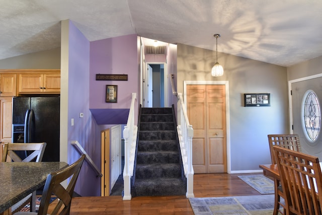 foyer entrance with lofted ceiling, a textured ceiling, and dark hardwood / wood-style flooring