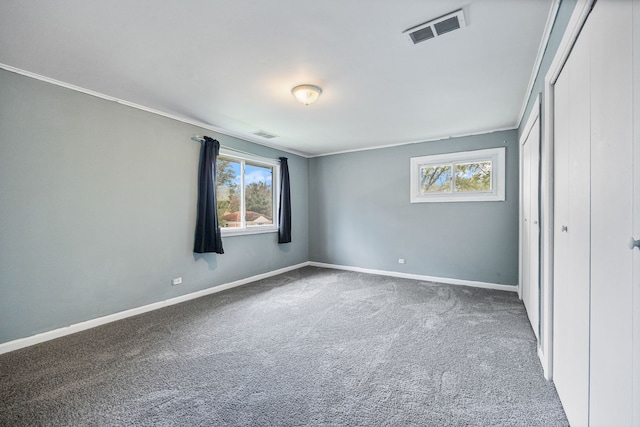 unfurnished bedroom featuring crown molding, multiple windows, visible vents, and carpet floors