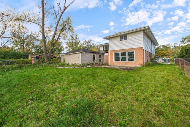 rear view of house with brick siding, fence, and a lawn