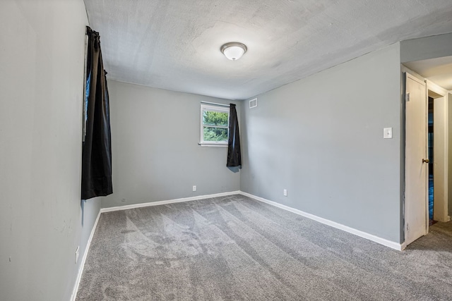 carpeted spare room with a textured ceiling, baseboards, and visible vents