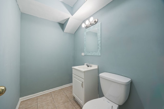 half bath with toilet, tile patterned floors, vanity, and baseboards