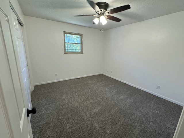 unfurnished bedroom featuring a closet, a textured ceiling, dark carpet, and ceiling fan