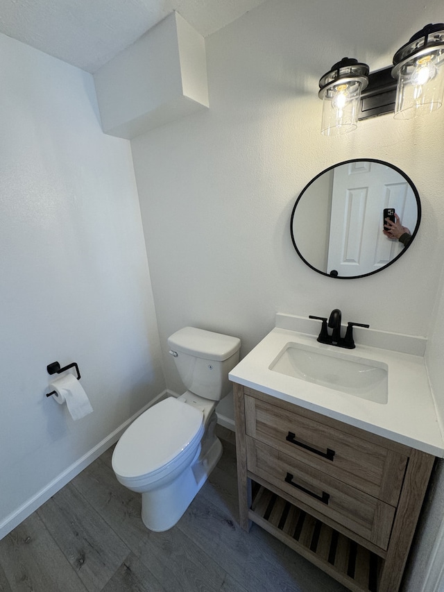 bathroom with toilet, vanity, and wood-type flooring