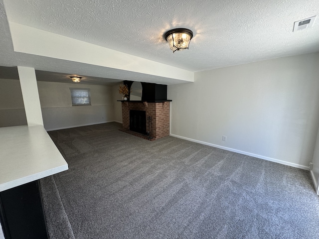 unfurnished living room featuring dark colored carpet, a textured ceiling, and a brick fireplace