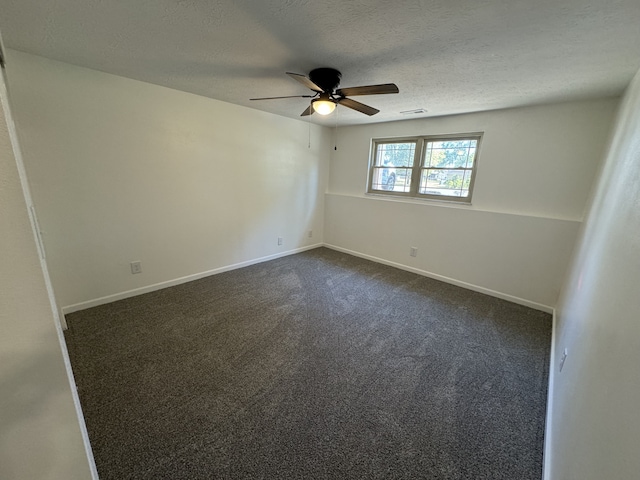 empty room with ceiling fan, a textured ceiling, and dark carpet