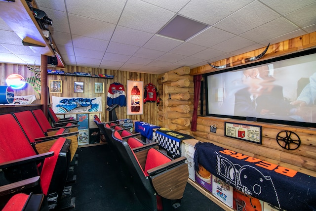 home theater featuring a drop ceiling, wood walls, and log walls