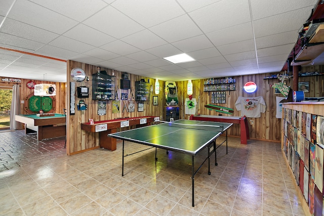 playroom with pool table, a paneled ceiling, and wood walls