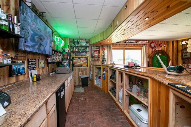 kitchen with a paneled ceiling, wood walls, and dishwasher