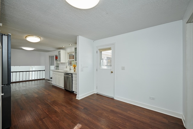 kitchen featuring appliances with stainless steel finishes, white cabinetry, a textured ceiling, dark wood-type flooring, and sink