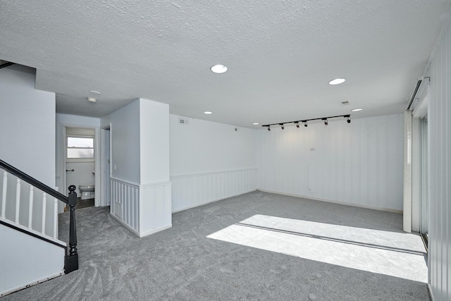 carpeted empty room with a textured ceiling, visible vents, a wainscoted wall, and recessed lighting