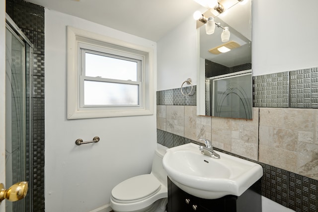 bathroom featuring toilet, vanity, tile walls, and a shower with door