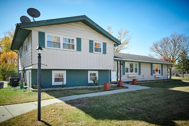 tri-level home featuring central air condition unit and a front lawn