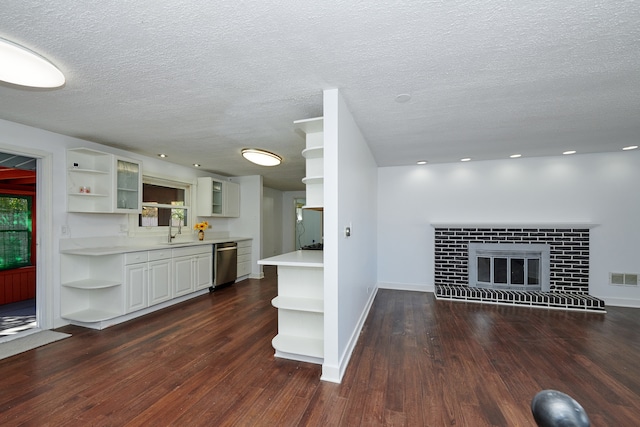 interior space featuring stainless steel dishwasher, dark wood-type flooring, sink, and a brick fireplace