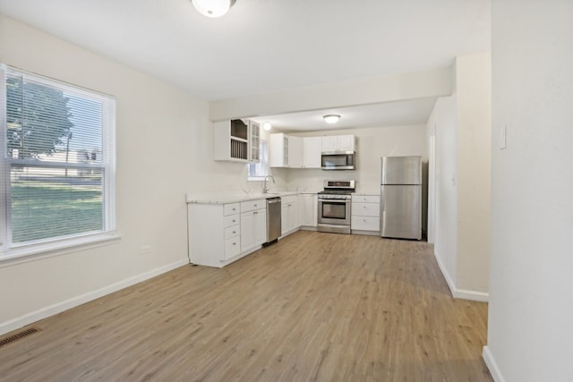 kitchen featuring sink, white cabinetry, stainless steel appliances, and light wood-type flooring