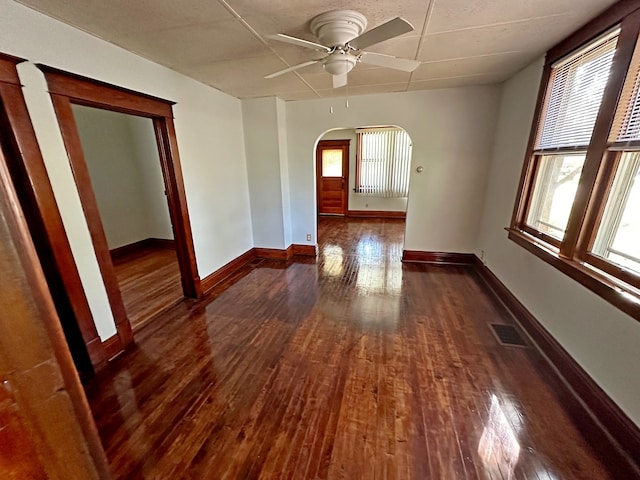 unfurnished room with a healthy amount of sunlight, ceiling fan, and dark hardwood / wood-style flooring