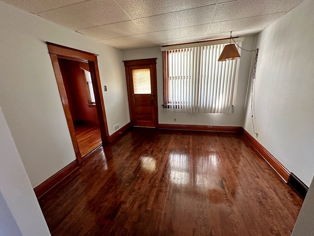 interior space featuring dark wood-type flooring and a drop ceiling