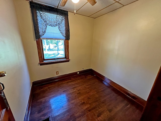 spare room featuring dark wood-type flooring, a paneled ceiling, and ceiling fan