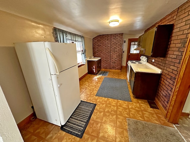 kitchen with brick wall, sink, vaulted ceiling, and white appliances