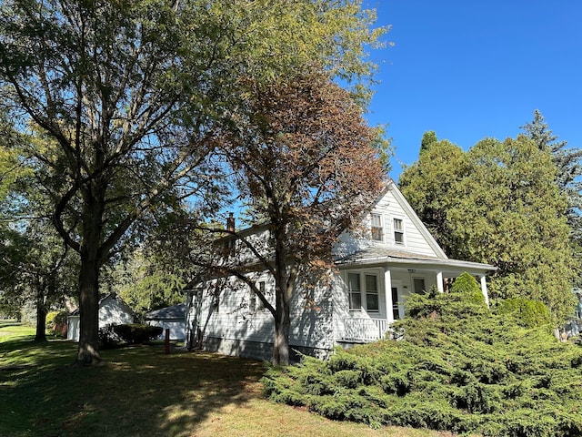 view of side of home with a porch and a yard