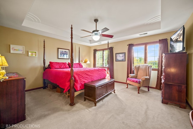 carpeted bedroom featuring ceiling fan and a raised ceiling