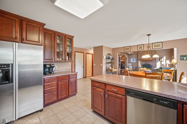 kitchen featuring pendant lighting, a brick fireplace, stainless steel appliances, and light tile patterned floors