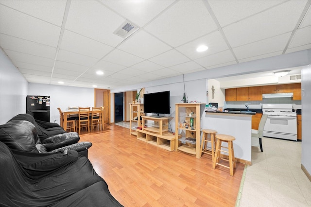 living room with light wood finished floors, a paneled ceiling, visible vents, and recessed lighting
