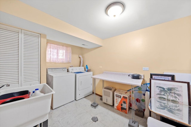 clothes washing area featuring marble finish floor, a sink, independent washer and dryer, and laundry area