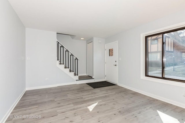 foyer with stairs, light wood-style floors, and baseboards