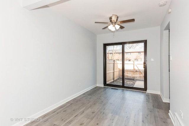 spare room featuring baseboards, light wood-type flooring, and ceiling fan