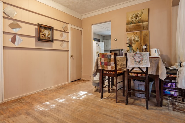 dining space with crown molding, hardwood / wood-style flooring, and a textured ceiling