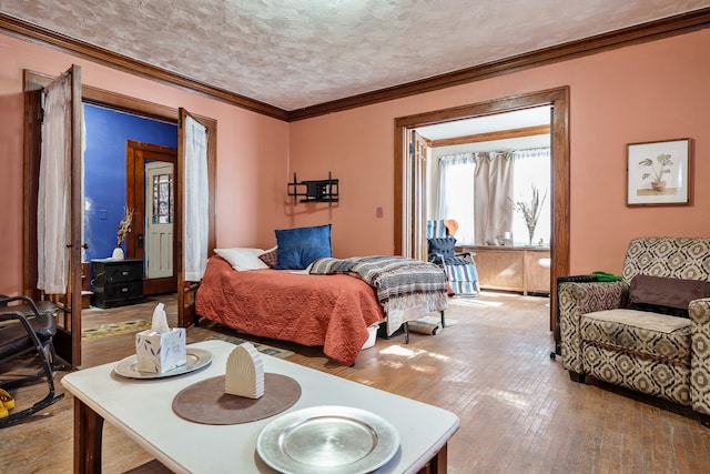 bedroom with crown molding, hardwood / wood-style flooring, and a textured ceiling