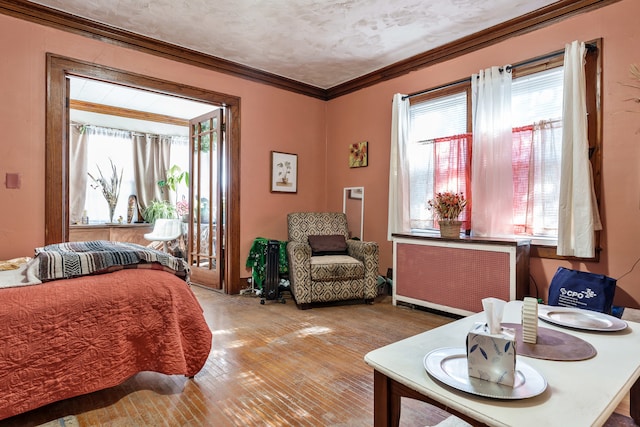 bedroom with crown molding, light wood-type flooring, and radiator