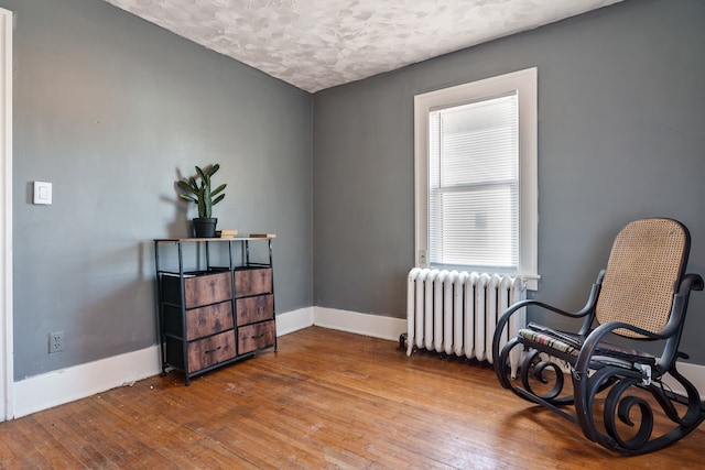 sitting room with radiator, a textured ceiling, and hardwood / wood-style floors