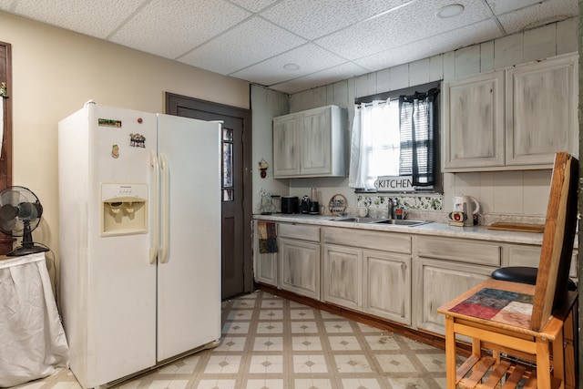 kitchen featuring white fridge with ice dispenser, a paneled ceiling, and sink